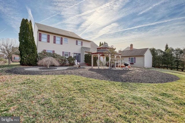 back of property with a gazebo, a yard, and fence