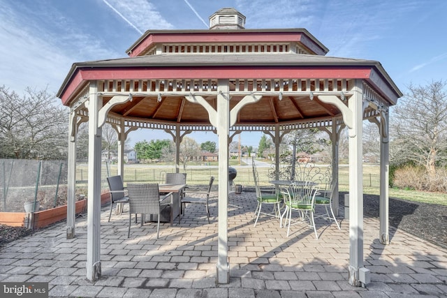 view of patio featuring a gazebo, outdoor dining space, and fence