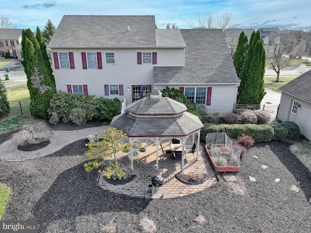 rear view of house featuring a gazebo, fence, roof with shingles, and a patio area