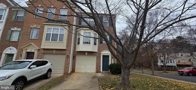 townhome / multi-family property featuring a garage, brick siding, and driveway