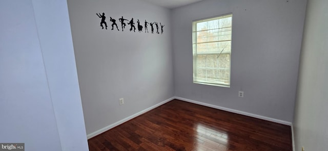 spare room featuring dark wood-type flooring and baseboards