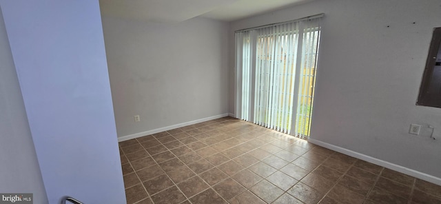 unfurnished room with baseboards and dark tile patterned floors