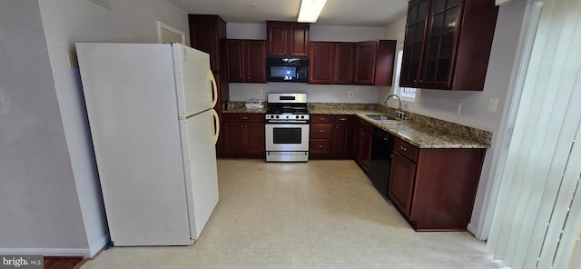 kitchen featuring black appliances, a sink, light stone counters, glass insert cabinets, and light floors