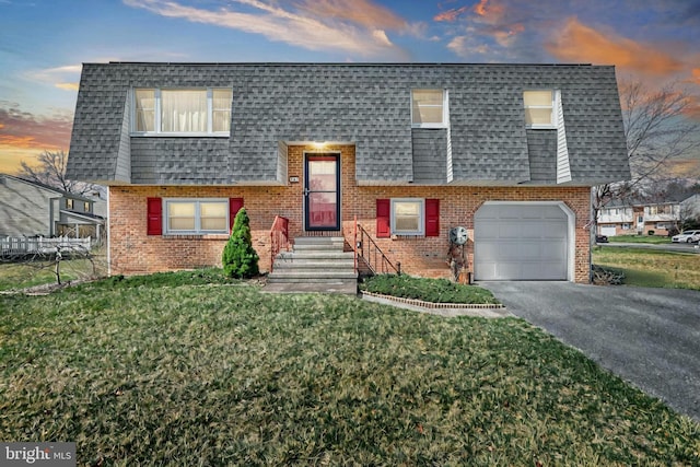 view of front facade with driveway, mansard roof, an attached garage, a shingled roof, and brick siding