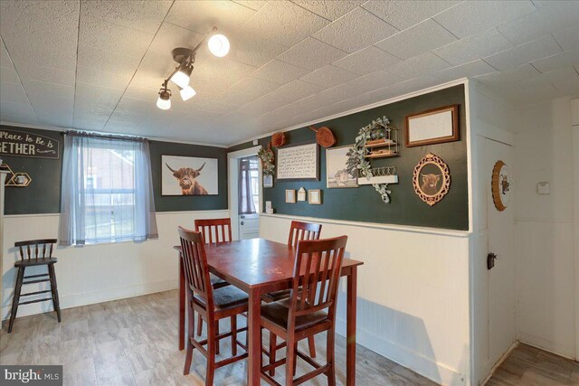 dining room with wood finished floors and a wainscoted wall