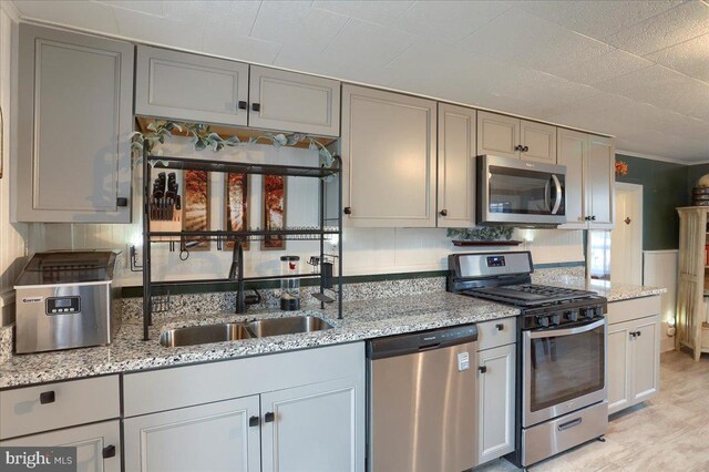 kitchen featuring a sink, light stone countertops, gray cabinets, and stainless steel appliances