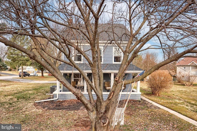 view of front facade featuring a front lawn and roof with shingles