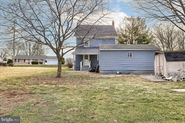 back of house with an outbuilding, a yard, a chimney, entry steps, and a storage unit