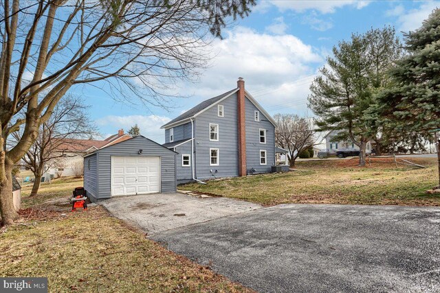 view of property exterior featuring cooling unit, a yard, a chimney, a garage, and aphalt driveway