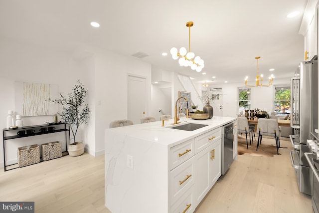 kitchen featuring visible vents, an inviting chandelier, stainless steel appliances, a sink, and light wood-type flooring