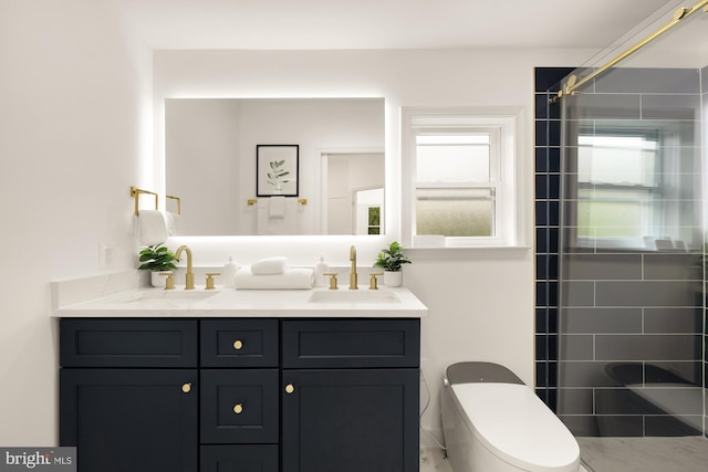 bathroom with double vanity, tiled shower, toilet, and a sink