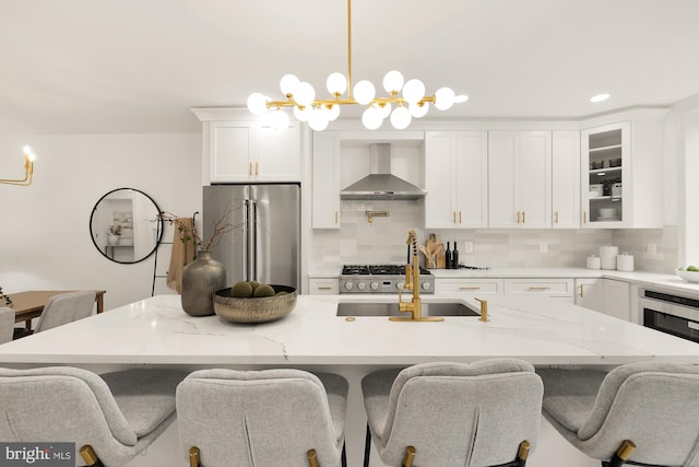 kitchen featuring decorative backsplash, appliances with stainless steel finishes, a kitchen breakfast bar, white cabinetry, and wall chimney exhaust hood