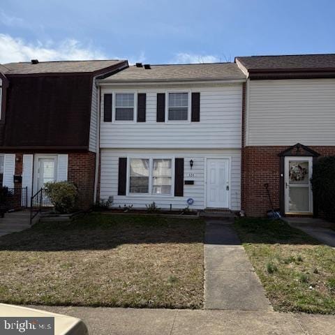 townhome / multi-family property featuring brick siding and a front lawn