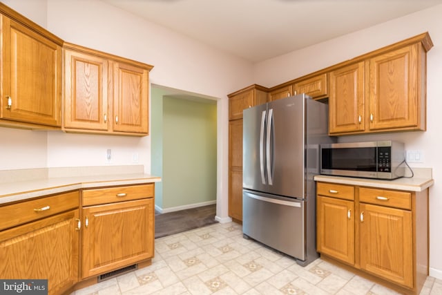 kitchen with visible vents, brown cabinets, stainless steel appliances, light countertops, and baseboards