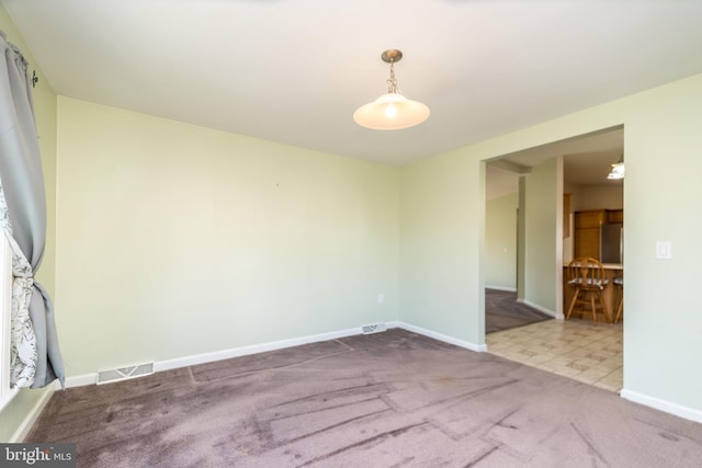 carpeted empty room with visible vents and baseboards