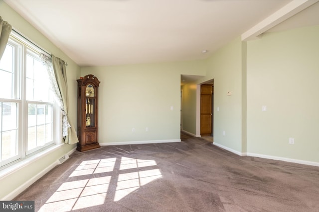 carpeted empty room with visible vents, baseboards, and vaulted ceiling