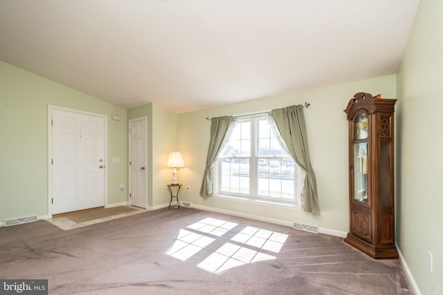 carpeted empty room with lofted ceiling, baseboards, and visible vents