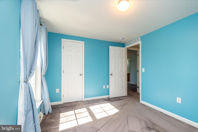 unfurnished bedroom with carpet flooring, baseboards, and a closet