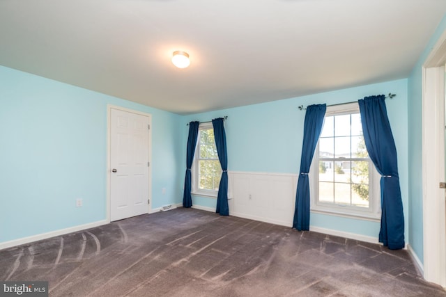 spare room with wainscoting, baseboards, and carpet floors