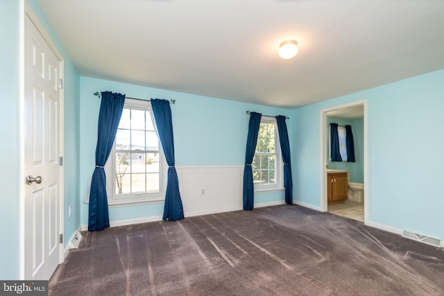 carpeted spare room featuring plenty of natural light, baseboards, and visible vents