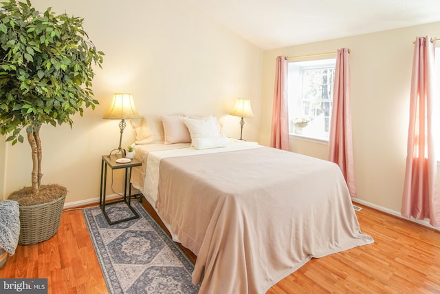 bedroom with lofted ceiling, baseboards, and wood finished floors