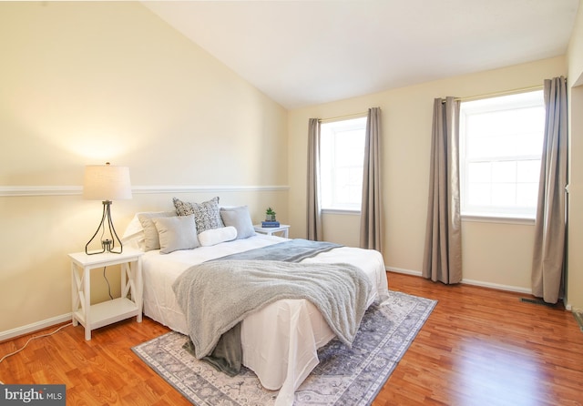 bedroom featuring light wood-style flooring, baseboards, and lofted ceiling