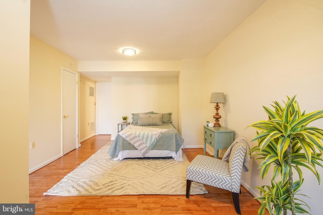 bedroom with visible vents, baseboards, and wood finished floors