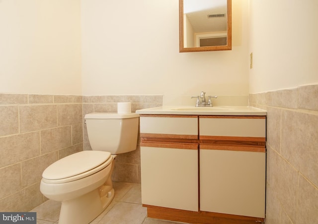 bathroom with visible vents, toilet, tile walls, tile patterned flooring, and vanity