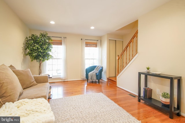 living room with light wood finished floors, visible vents, recessed lighting, and stairway