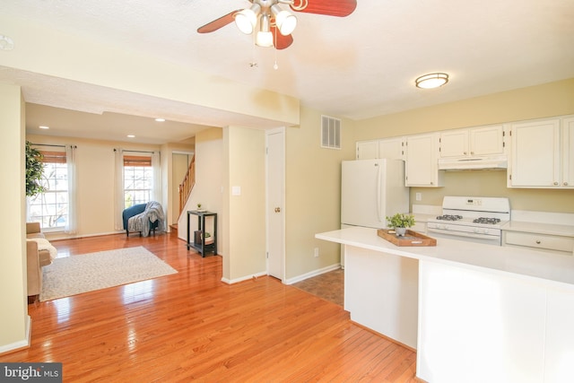 kitchen featuring white appliances, light wood finished floors, light countertops, and under cabinet range hood