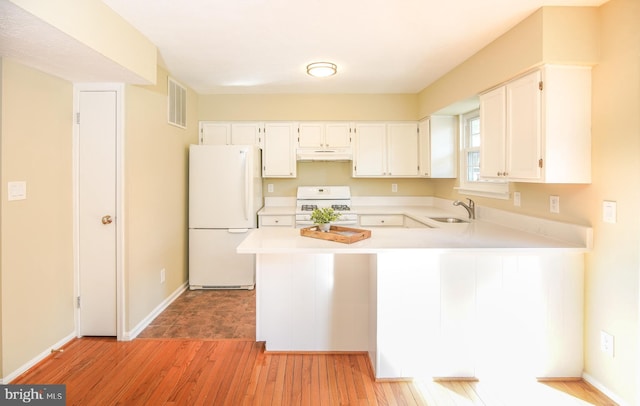 kitchen featuring visible vents, under cabinet range hood, a sink, white appliances, and light countertops