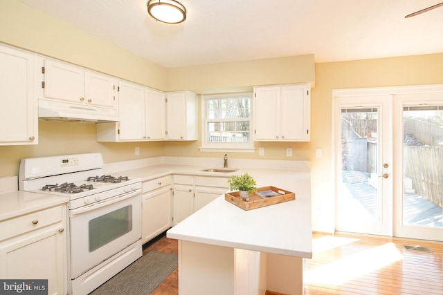 kitchen featuring light countertops, white range with gas stovetop, and under cabinet range hood