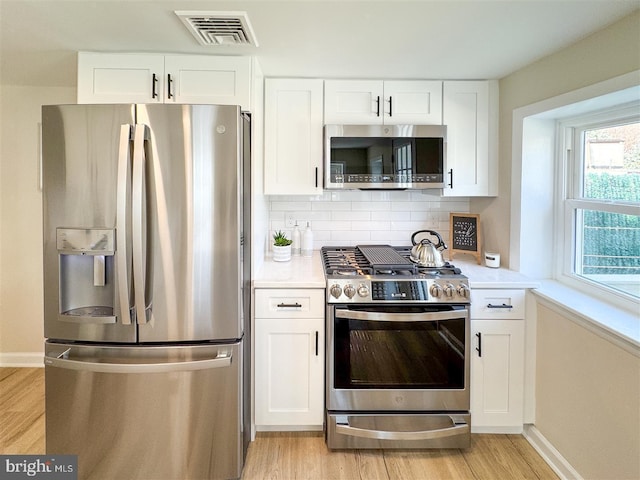 kitchen featuring light wood-type flooring, visible vents, backsplash, stainless steel appliances, and light countertops