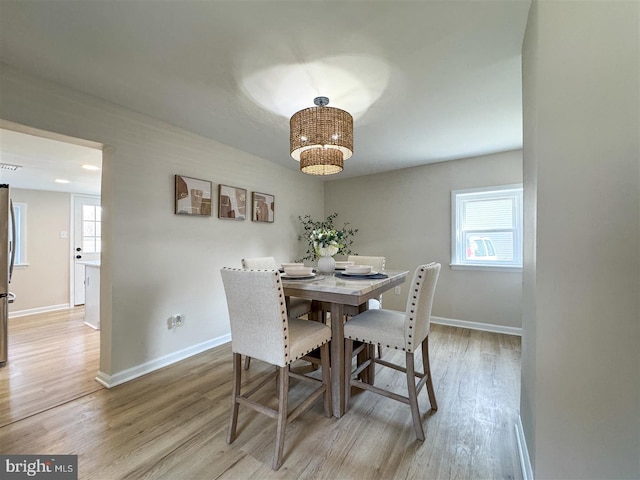 dining space featuring a wealth of natural light, a chandelier, baseboards, and wood finished floors