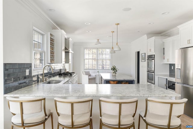 kitchen with a sink, a healthy amount of sunlight, appliances with stainless steel finishes, and ornamental molding