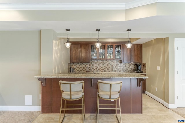 bar featuring decorative backsplash, hanging light fixtures, baseboards, and ornamental molding