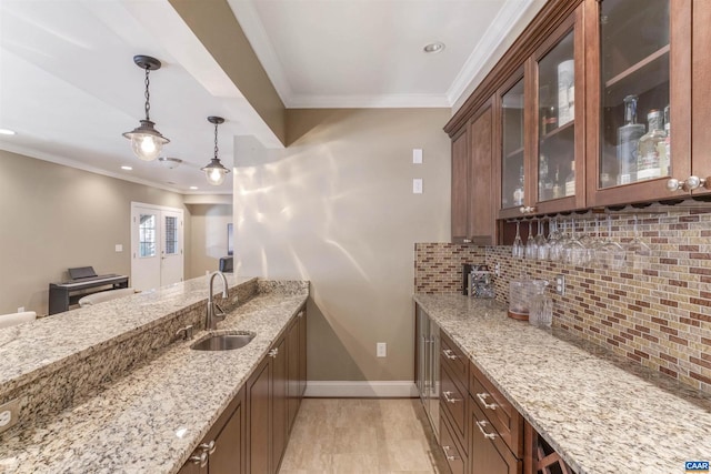 bar with decorative backsplash, ornamental molding, hanging light fixtures, and a sink