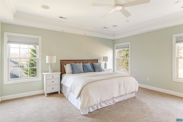 bedroom featuring a tray ceiling, multiple windows, light colored carpet, and ornamental molding