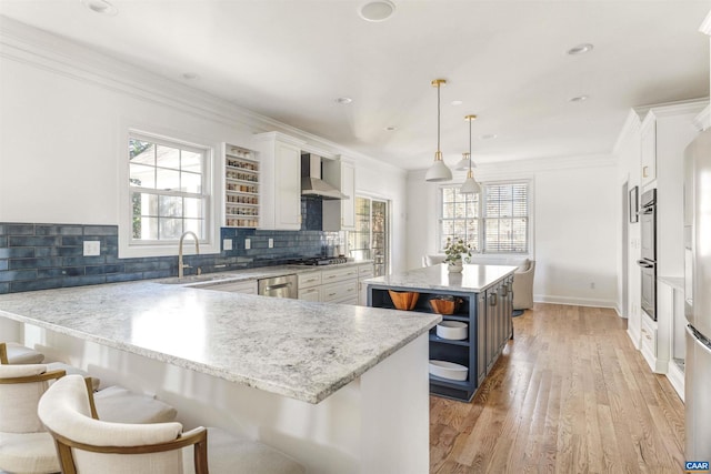 kitchen with open shelves, a sink, appliances with stainless steel finishes, white cabinetry, and wall chimney exhaust hood