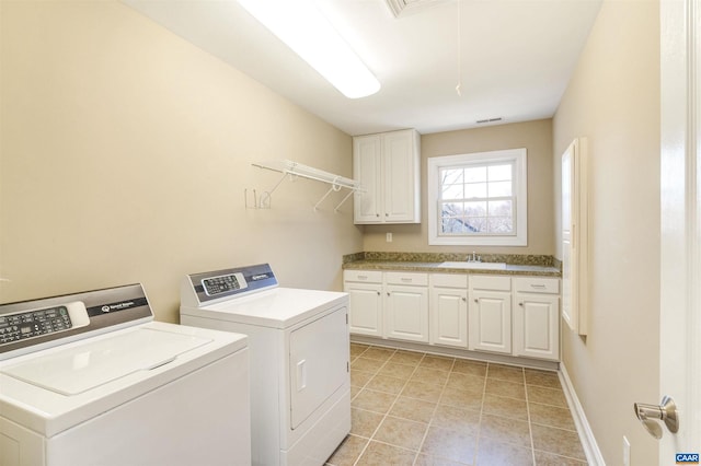 washroom with visible vents, attic access, cabinet space, a sink, and washing machine and dryer