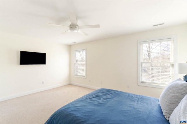 bedroom with visible vents, light colored carpet, baseboards, and ceiling fan