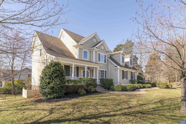 view of front of home featuring a porch, fence, a front yard, and roof with shingles