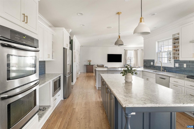 kitchen with ornamental molding, white cabinetry, stainless steel appliances, and a sink