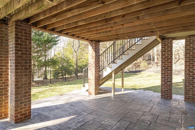 view of patio featuring stairway and fence