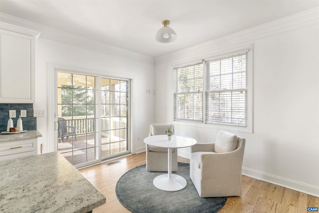 dining room featuring crown molding, light wood-style floors, baseboards, and visible vents