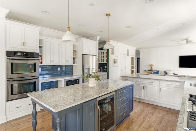 kitchen featuring light wood finished floors, wine cooler, white cabinets, appliances with stainless steel finishes, and a center island