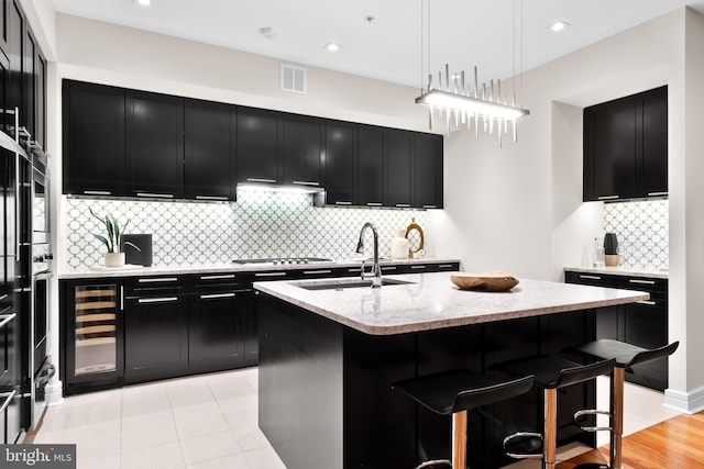 kitchen with wine cooler, visible vents, dark cabinetry, and a sink