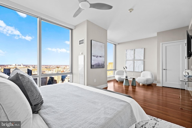 bedroom featuring visible vents, wood finished floors, floor to ceiling windows, baseboards, and ceiling fan