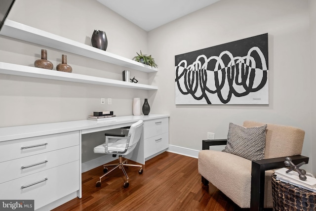 office with built in desk, dark wood-type flooring, and baseboards