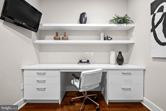 office area featuring dark wood finished floors, built in desk, and baseboards